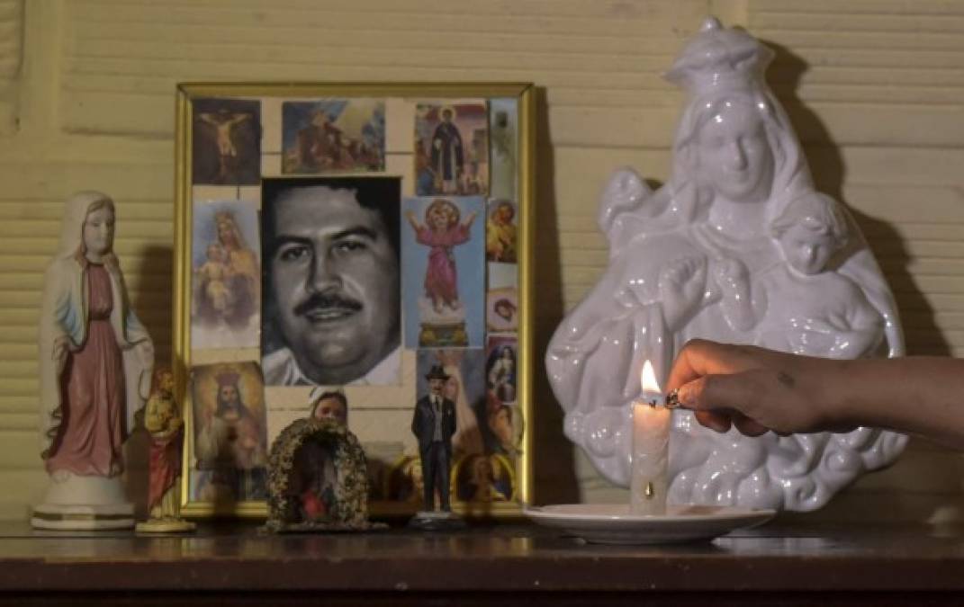 Maria Eugenia Castano, resident of Pablo Escobar neighborhood, lights a candle at the portrait of Colombian drug lord Pablo Escobar in her house on November 28, 2018, in Medellin, Colombia. - December 2 marks the 25th anniversary of Escobar's death. (Photo by Raul ARBOLEDA / AFP)