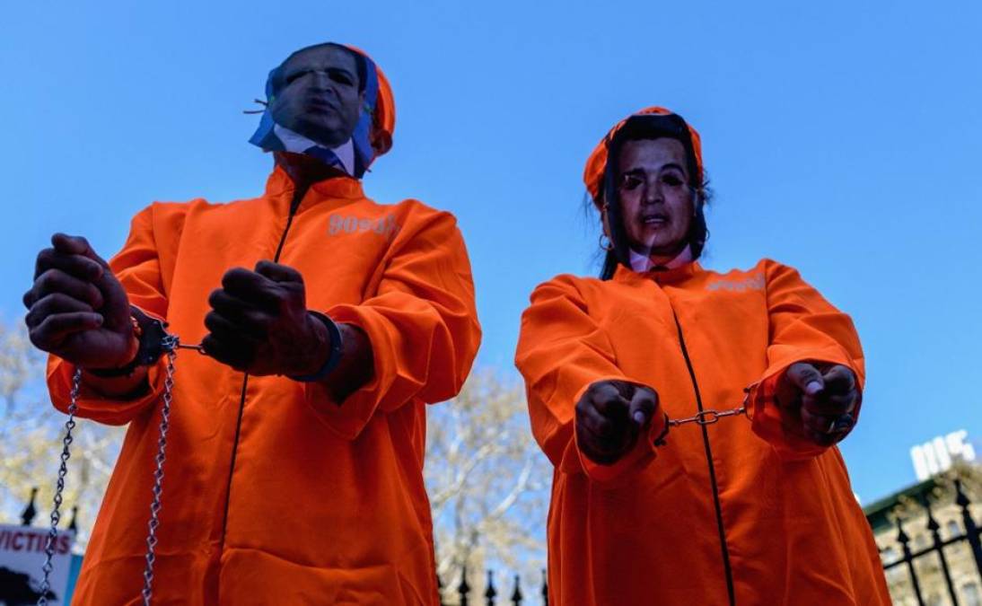 En esta imagen se aprecia a dos personas vistiendo traje naranja, similar al de los reclusos, con fotografías de Juan Orlando Hernández y su hermano “Tony”. 