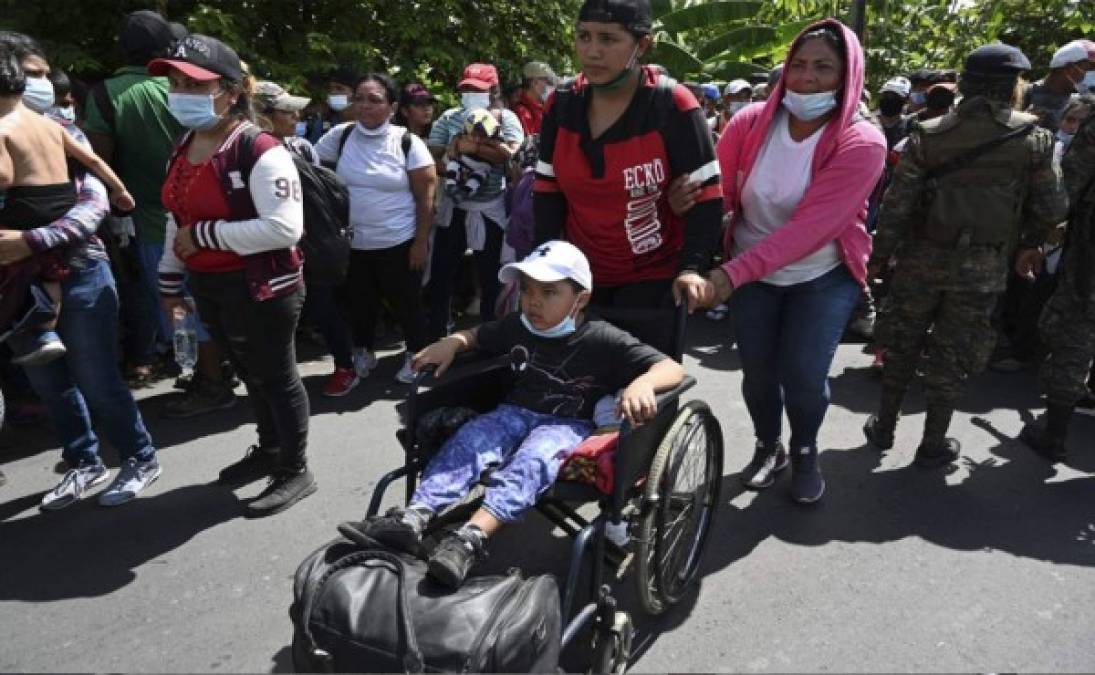 Migrantes hondureños empujan a un niño en silla de ruedas. Foto AFP