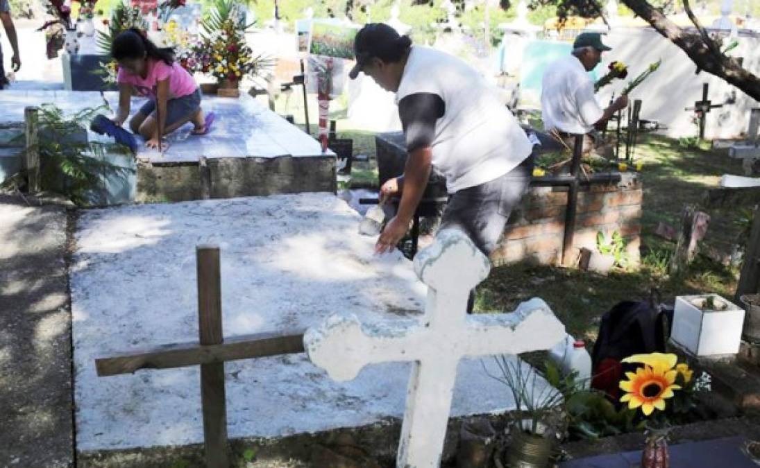 un hombre llega a colocar flores a la tumba de un familiar este sábado durante la conmemoración del Día de Muertos, en un campo santo de Tegucigalpa (Honduras).