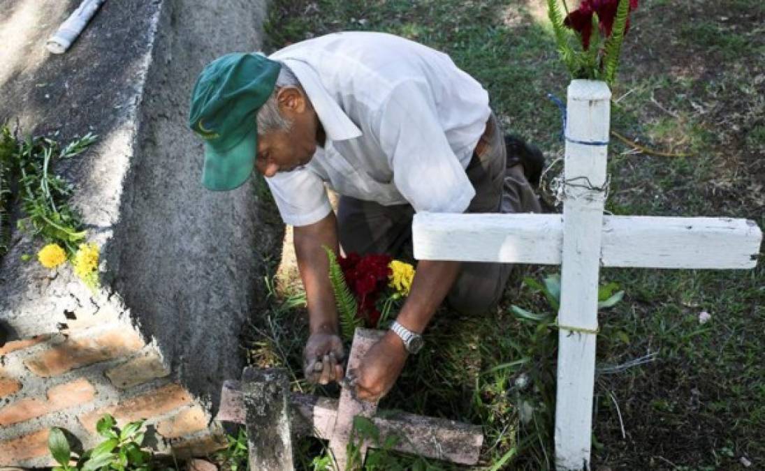 Un hombre poneflores a la tumba de un familiar este sábado durante la conmemoración del Día de Muertos, en un campo santo de Tegucigalpa.