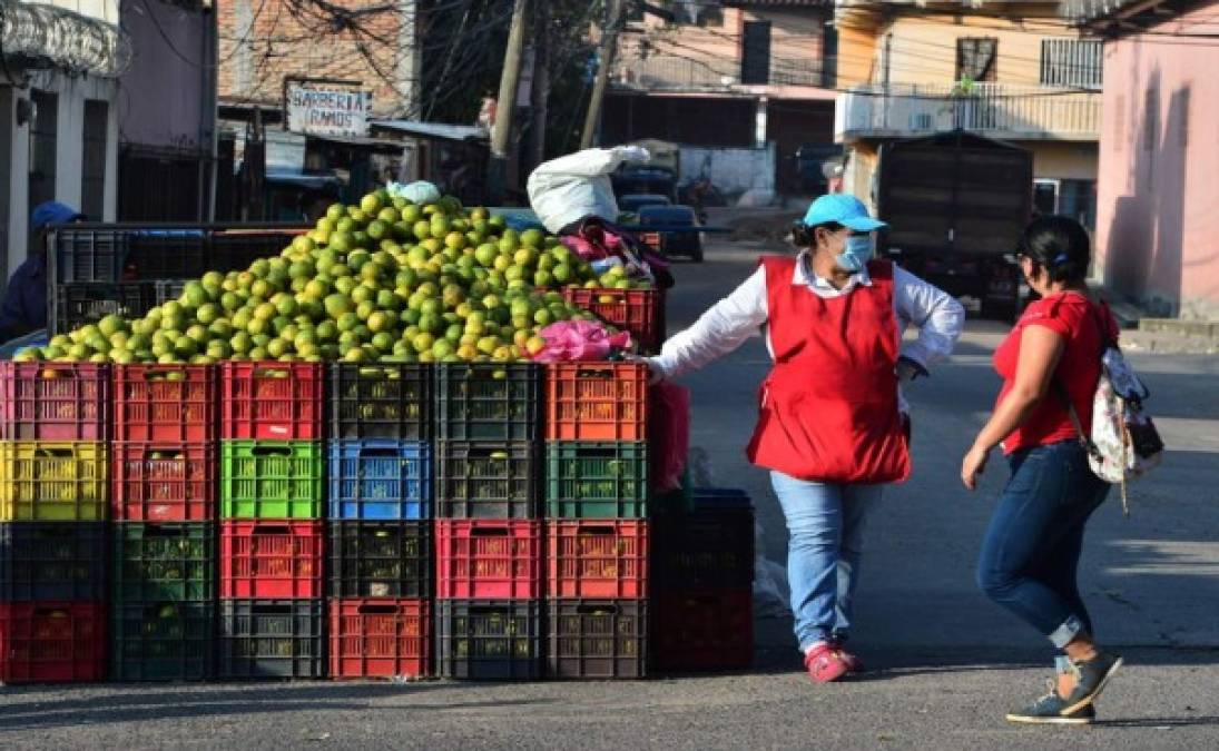 Una mujer vende fruta en una calle de Tegucigalpa luego de anunciarse la reanudación de la actividad económica en medio de la pandemia de COVID-19. Foto AFP
