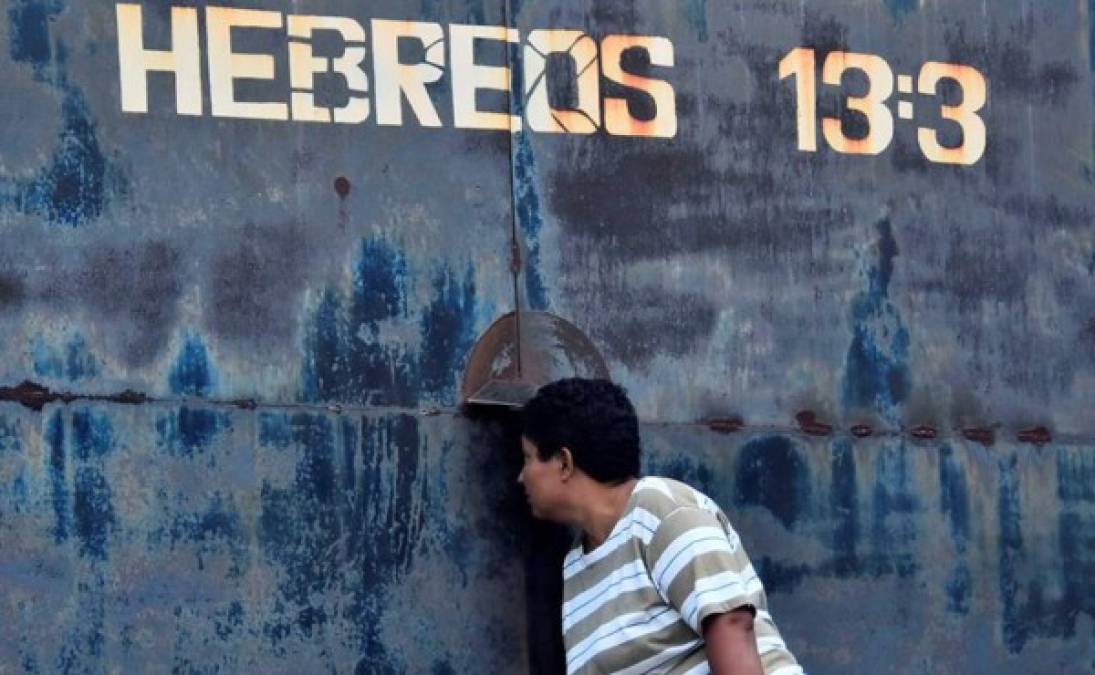 Una mujer observa por una rendija en una puerta del centro penitenciario de Tela, este sábado en el municipio de Atlántida (Honduras). Al menos 18 presos murieron ayer en la cárcel de Tela, departamento caribeño de Atlántida, donde se dio un tiroteo entre reclusos por causas que investigan las autoridades.