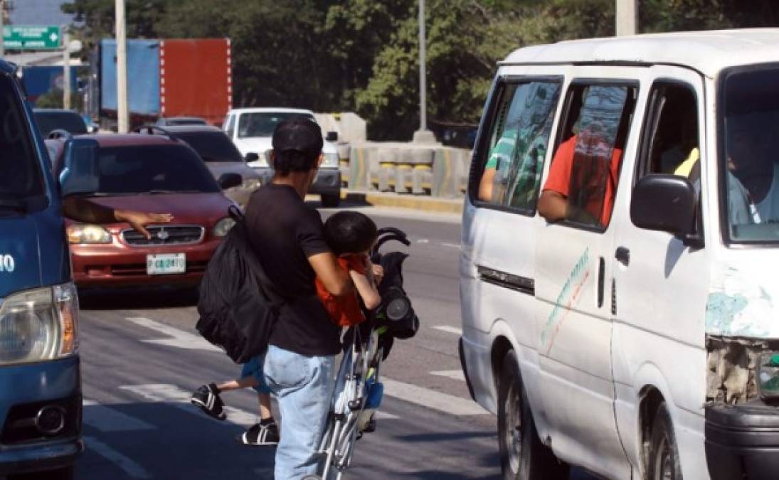 Padres de menores de edad hacen esfuerzos sobrehumanos para poder llevar a salvo a sus hijos en los cruces de las calles en San Pedro Sula.
