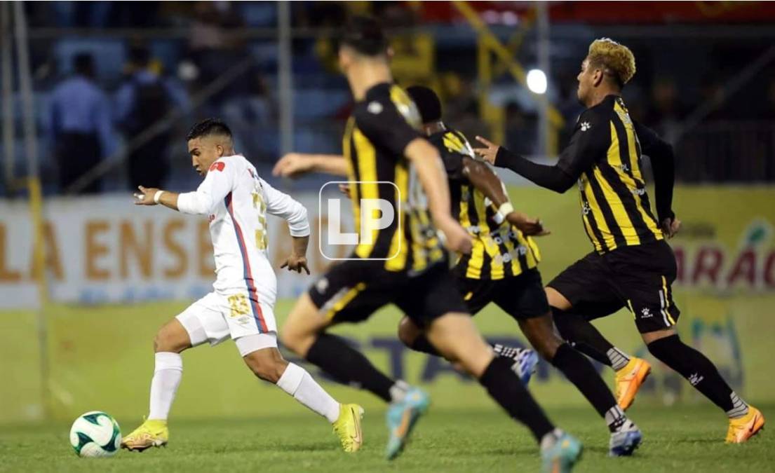 Michaell Chirinos corriendo con el balón y varios jugadores del Real España lo persiguen.