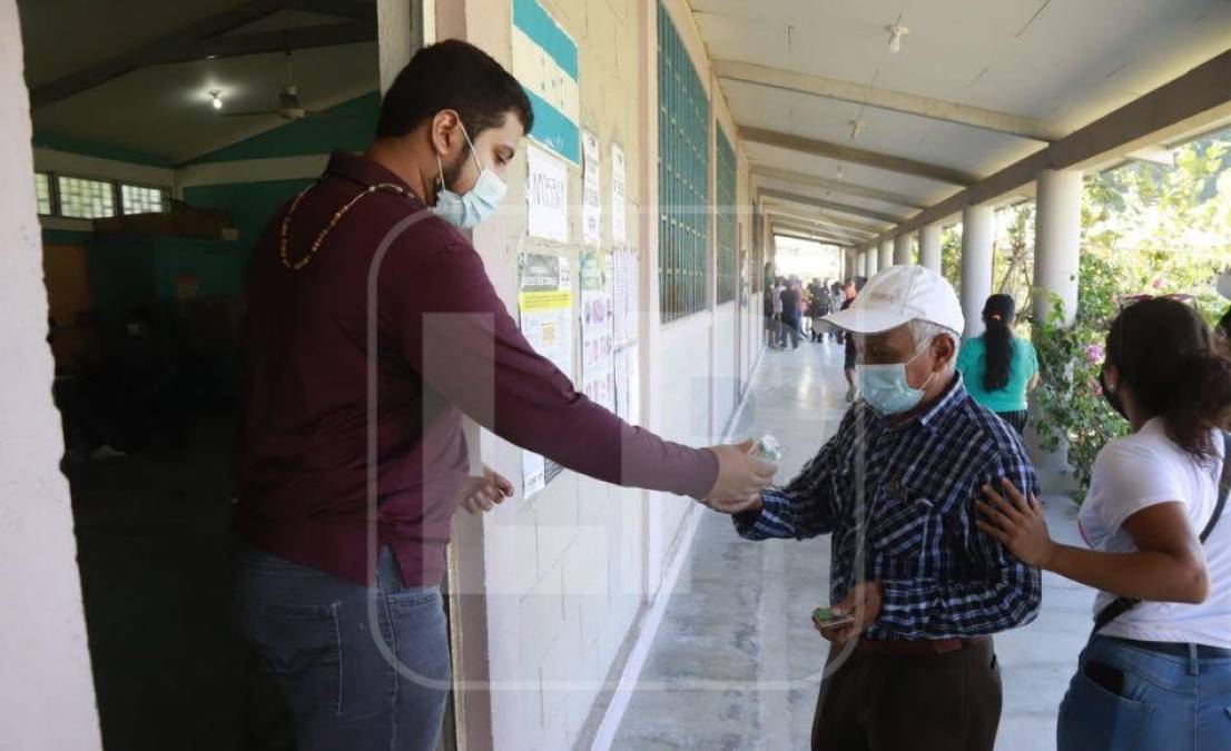 Miembros de las Mesas Electorales Receptoras aplican gel antibacterial a votantes antes de ingresar a las urnas.