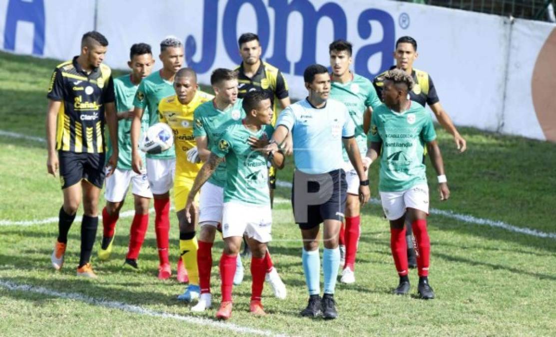 Los jugadores de Marathón y Real España reclaman al árbitro Raúl Castro tras pitar el penal a favor del equipo local en el inicio del juego.