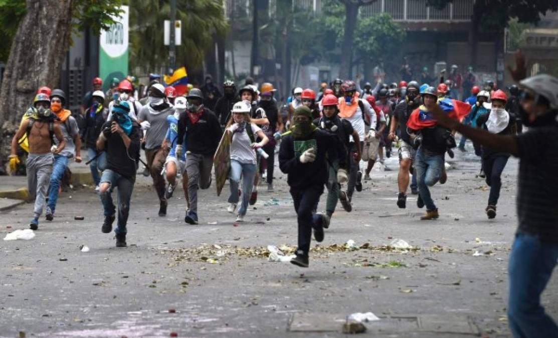 Opositores venezolanos corren en estampida durante uno de los enfrentamientos con las fuerza de seguridad.