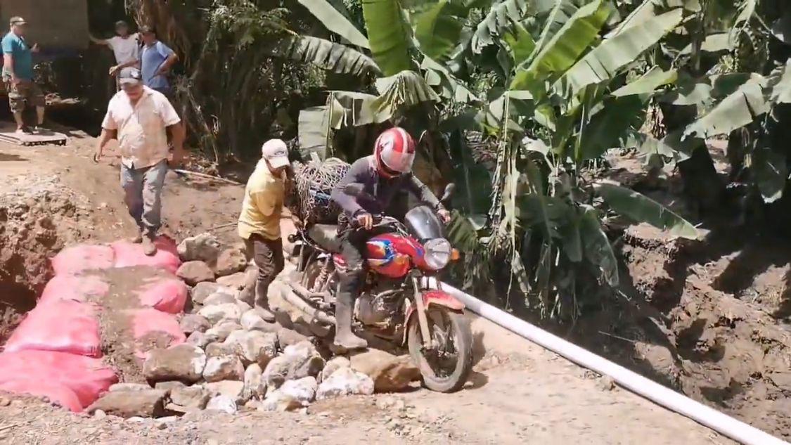 Un conductor de moto pasa por el tramo dañado.