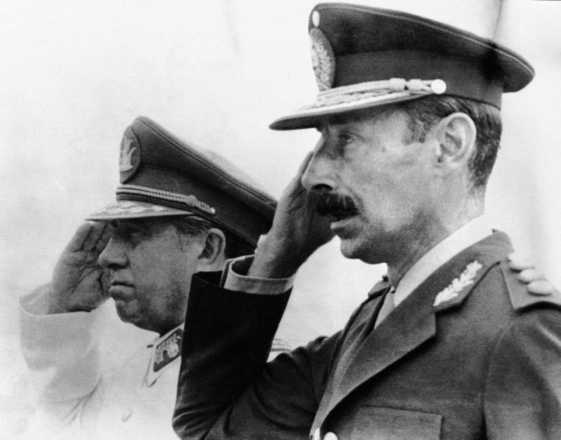 (ARCHIVOS) El dictador chileno (1973-1990), el general Augusto Pinochet (izq.), y su homólogo argentino, el general Jorge Videla, saludan en Chile en 1978. Pinochet tomó el poder mediante un sangriento golpe de Estado respaldado por la CIA el 11 de septiembre de 1973, en el que se produjo el primer golpe de Estado del mundo.
