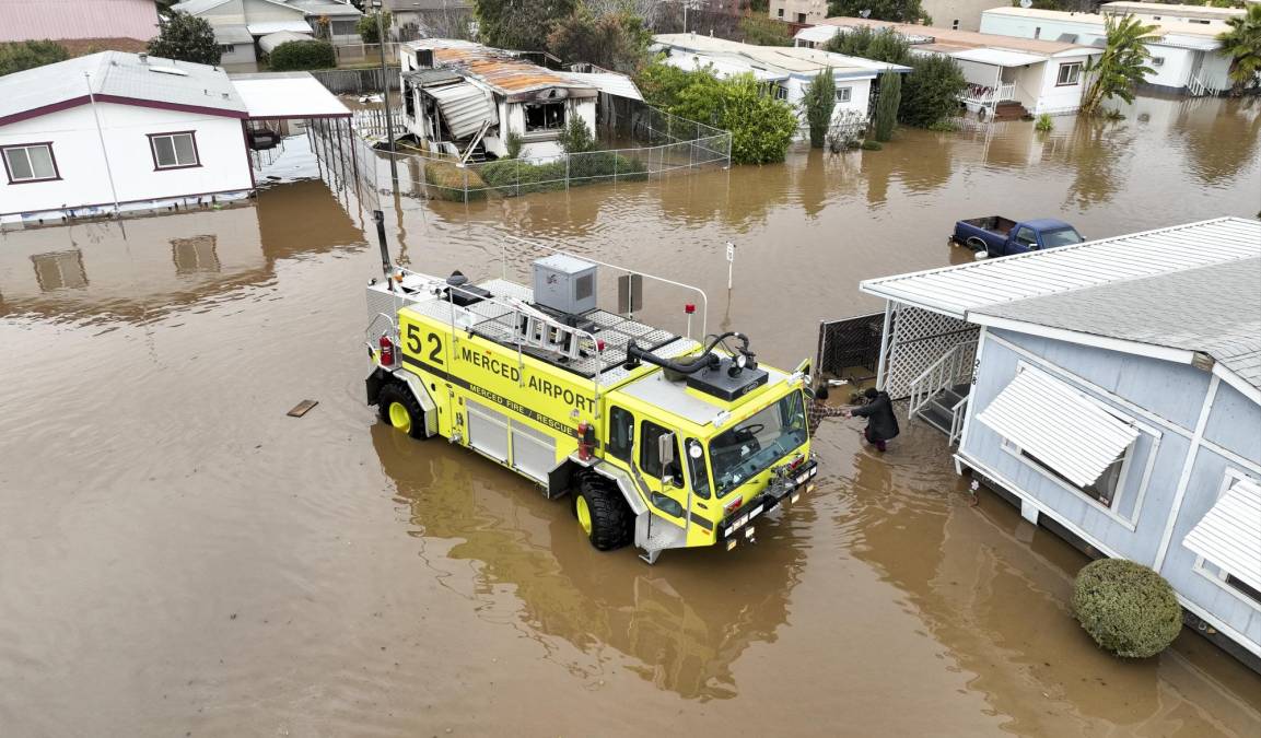This aerial view shows rescue crews assisting stranded residents in a flooded neighborhood in Merced, California on January 10, 2023. - A massive storm has arrived and is expected to cause widespread flooding throughout the state. (Photo by JOSH EDELSON / AFP)