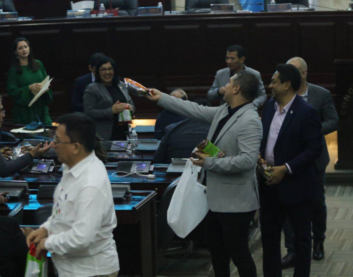 Diputados del Partido Libertad y Refundación (Libre) reparten churros (snack) y refrescos a sus colegas en la madrugada de este viernes mientras esperaban que terminara la primera sesión del pleno de magistrados de la Corte Suprema de Justicia que acaban de elegir en el Congreso Nacional.