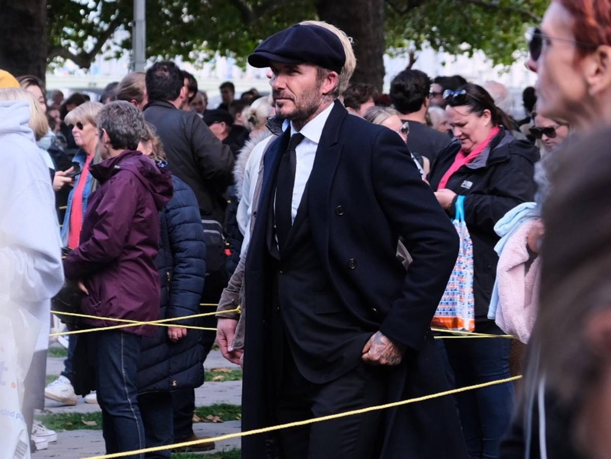 Beckham, de 47 años, fue descubierto por la prensa mientras esperaba en la fila, vestido con traje, corbata y abrigo negros. Llevaba también una gorra y un paraguas del mismo color.
