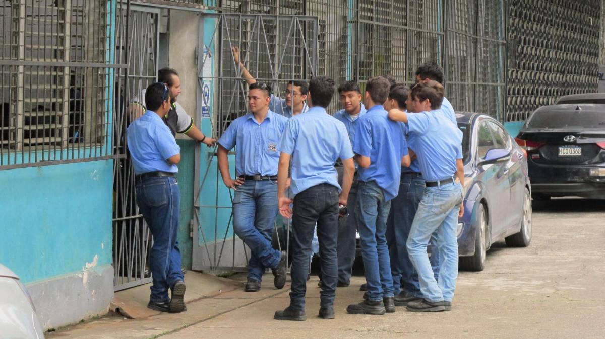 Un grupo de estudiantes conversan con su profesor fuera de los talleres del centro de formación técnica.
