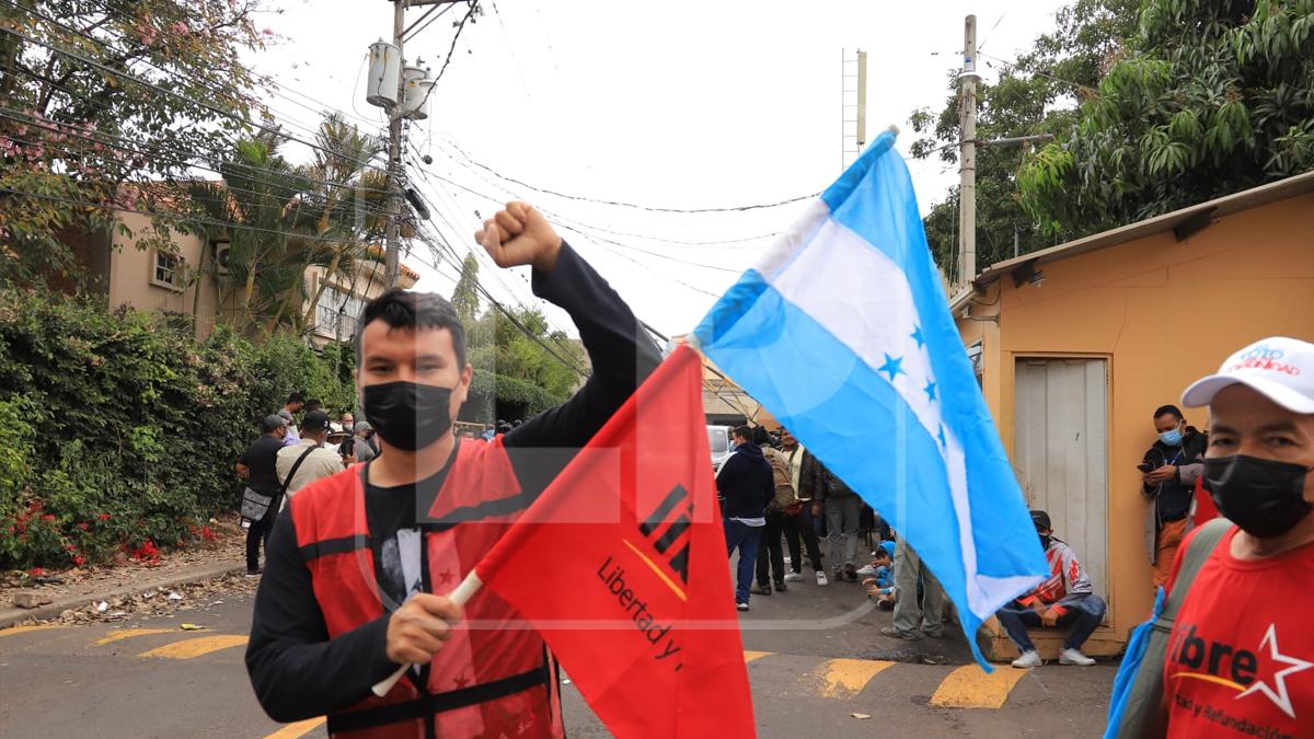 Un militantes del partido Libertad y Refundación (Libre) sostiene una bandera tras enterarse de la captura del expresidente Juan Orlando Hernández.