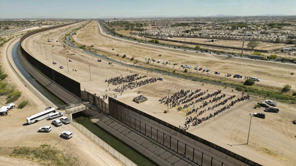 Fotografía aérea muestra hoy a cientos de migrantes mientras esperan junto al muro fronterizo en El Paso, Texas (EE.UU).