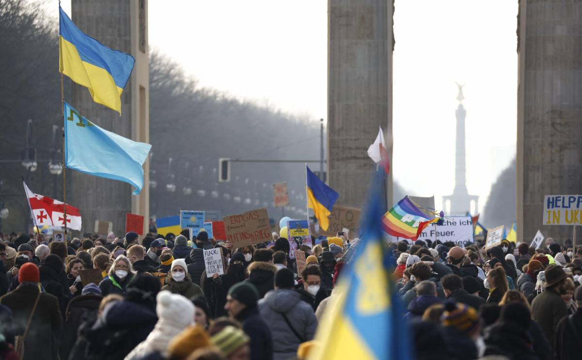 Los manifestantes con banderas ucranianas se paran bajo la Puerta de Brandenburgo en Berlín para manifestarse por la paz en Ucrania el 27 de febrero de 2022.