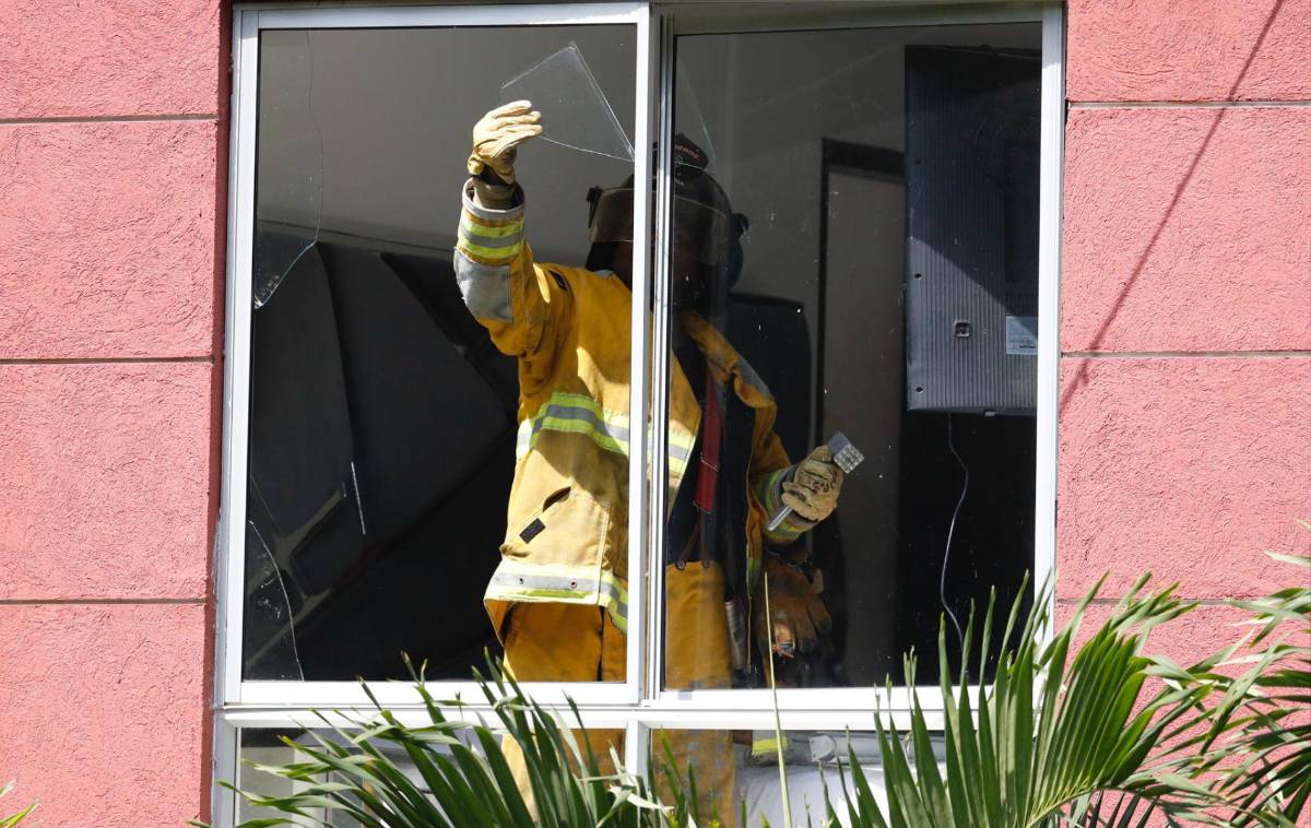 Un bombero revisa una ventana rota de una vivienda tras la explosión de una motocicleta en un puesto de control de la Policía de Colombia.