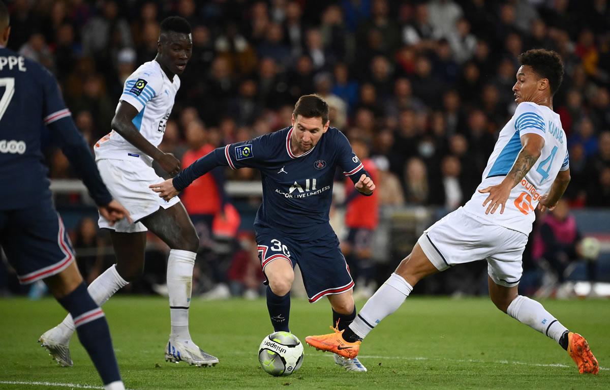 Lionel Messi passing between two Marseille footballers.