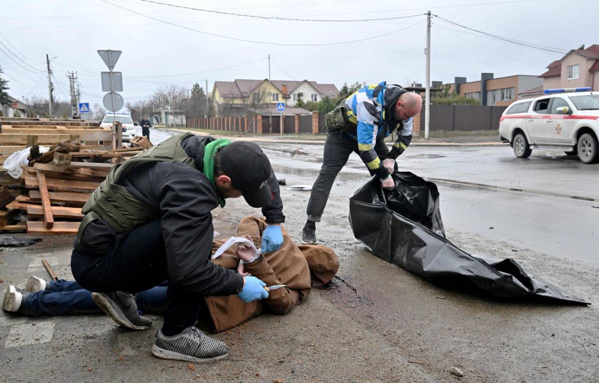 Un trabajador comunal corta la cuerda del cadáver de un hombre con las manos atadas a la espalda mientras un colega prepara una bolsa plástica para cadáveres para llevarlo a un automóvil que espera en la ciudad de Bucha, no lejos de la capital ucraniana de Kiev el 3 de abril. , 2022.