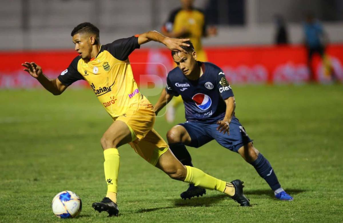 El defensor Getsel Montes del Real España conduce la pelota ante la marca del volante Diego Auzqui del Motagua.