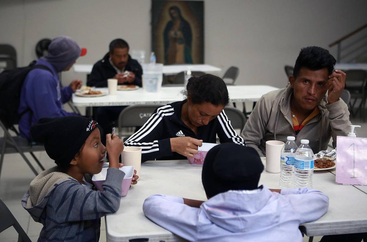 Una familia de migrantes recibe alimentos y se protege del frio en un albergue, el 4 de noviembre de 2023, en Ciudad Juárez.