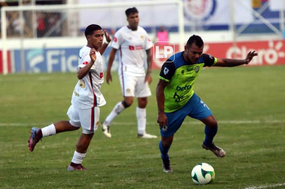 Mario Martínez conduce el balón ante la presión de Jared Velásquez del Olimpia.