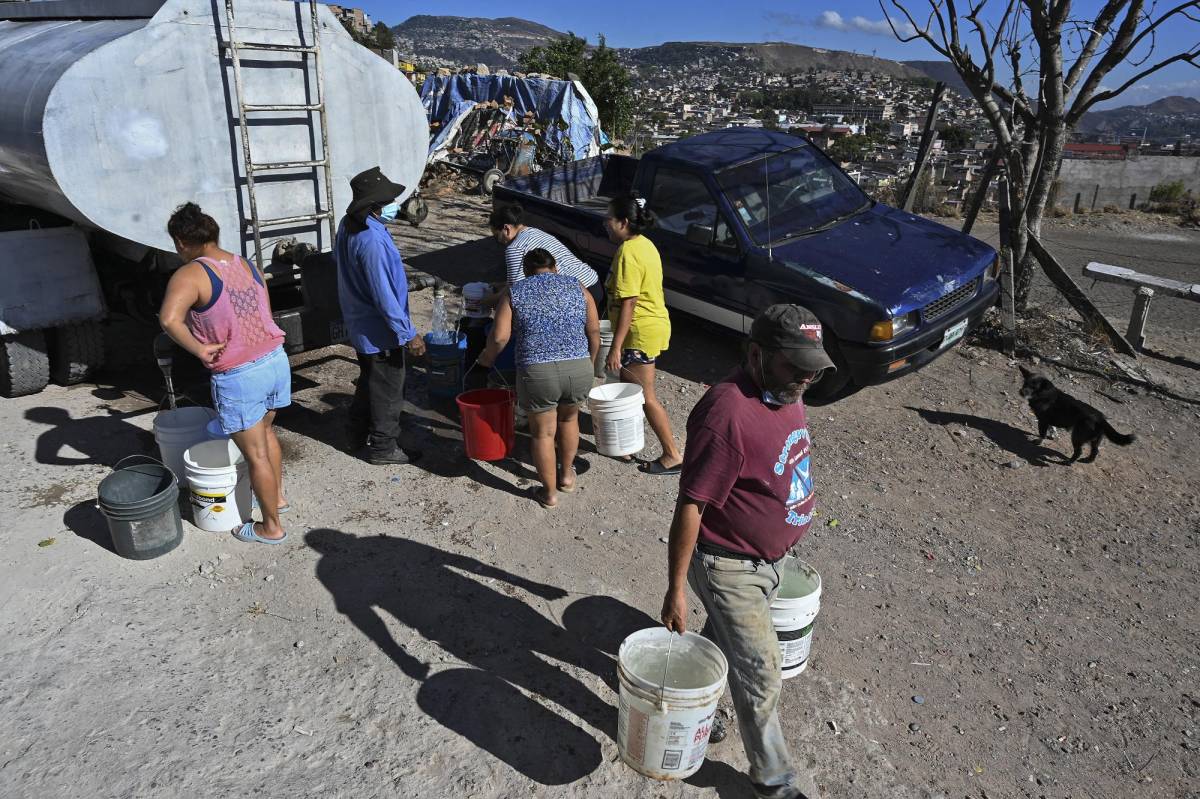 People obtain drinking water from a tanker on the outskirts of Tegucigalpa on March 22, 2022, on World Water Day. (Photo by Orlando SIERRA / AFP)