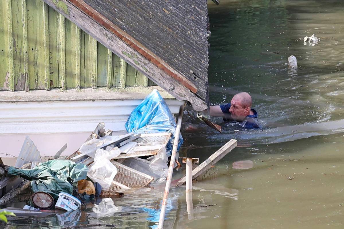 Un hombre nada alrededor de su casa tras las inundaciones ocasionadas por la destrucción de una represa en Jersón.