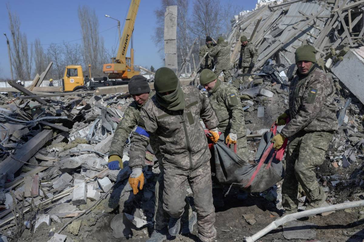 Soldados ucranianos cargan a un soldado muerto a través de los escombros en la escuela militar alcanzada por cohetes rusos el día anterior, en Mykolaiv.