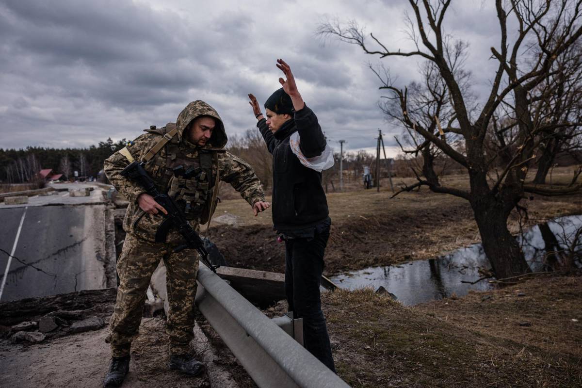 Militares ucranianos revisan a los civiles antes de permitirles el paso para abandonar la capital.