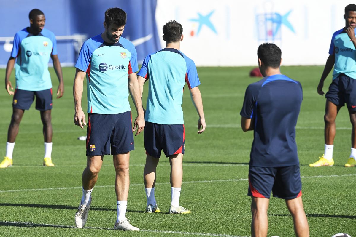 Xavi Hernández, atento al entrenamiento del Barcelona observando a Gerard Piqué.
