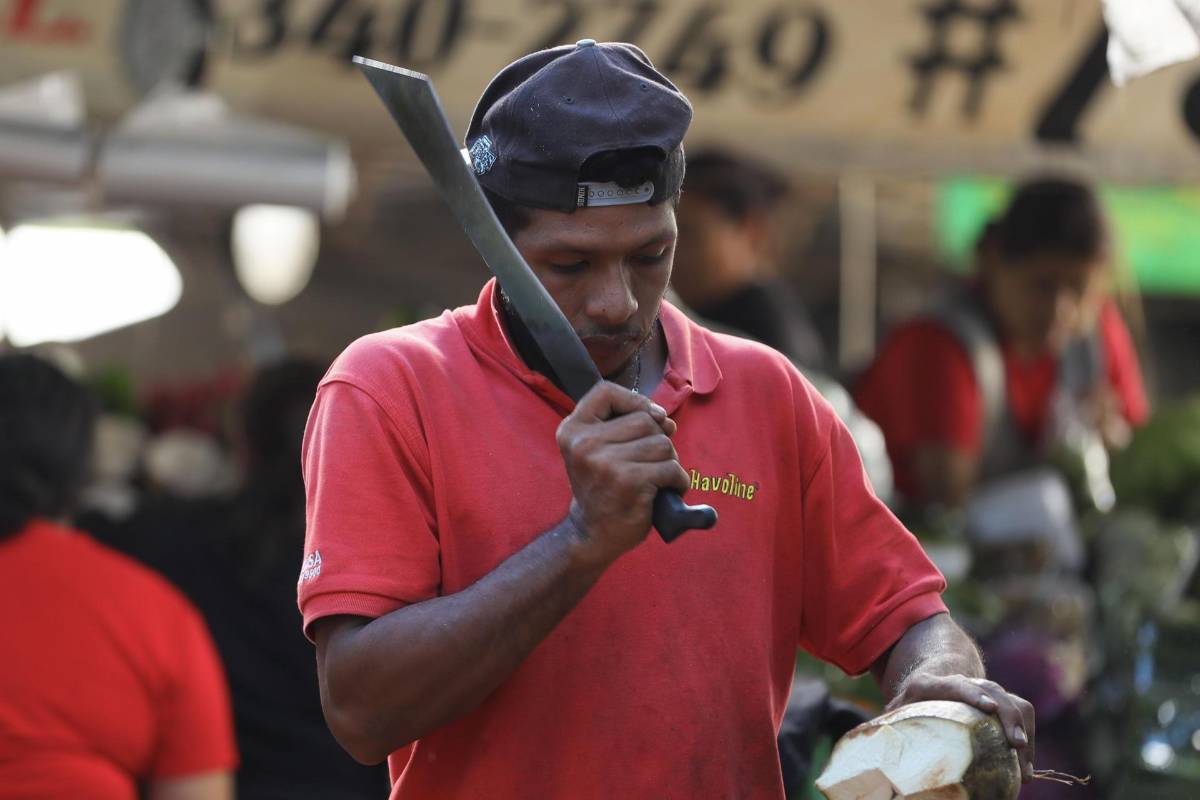 Un hombre quita la cáscara de un coco para su venta en un mercado, el 3 de noviembre de 2023, en Tegucigalpa (Honduras).