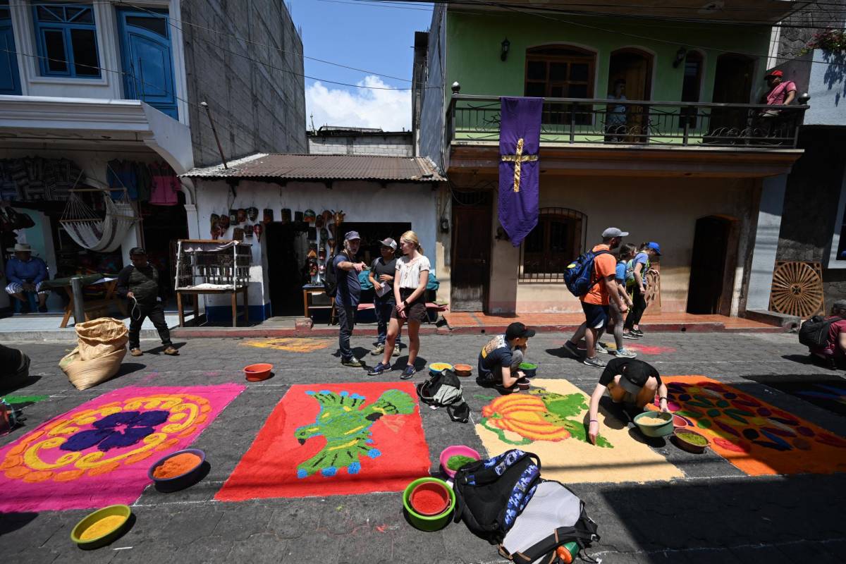 Los turistas admiran las alfombras de aserrín en Antigua Guatemala.