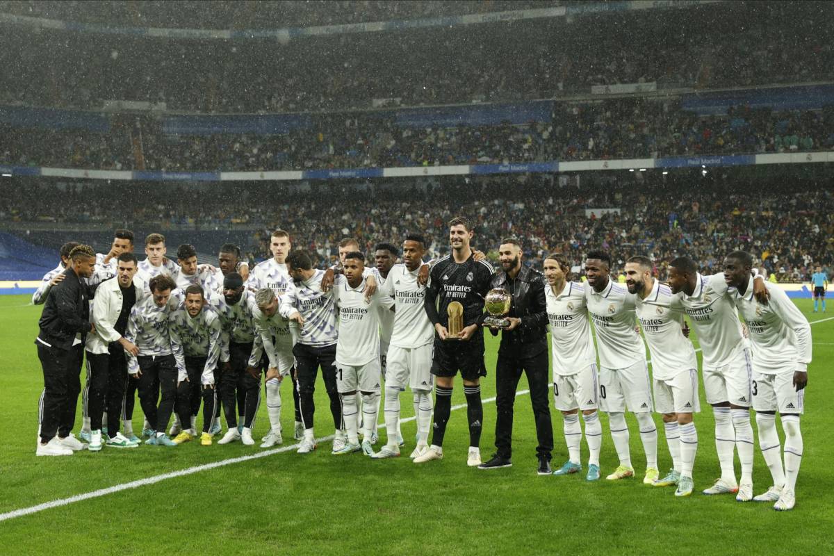 Los jugadores del Real Madrid, el francés Karim Benzema y el belga Thibaut Courtois, acompañados por sus compañeros posan con el Balón de Oro y el Trofeo Yashin respectivamente.