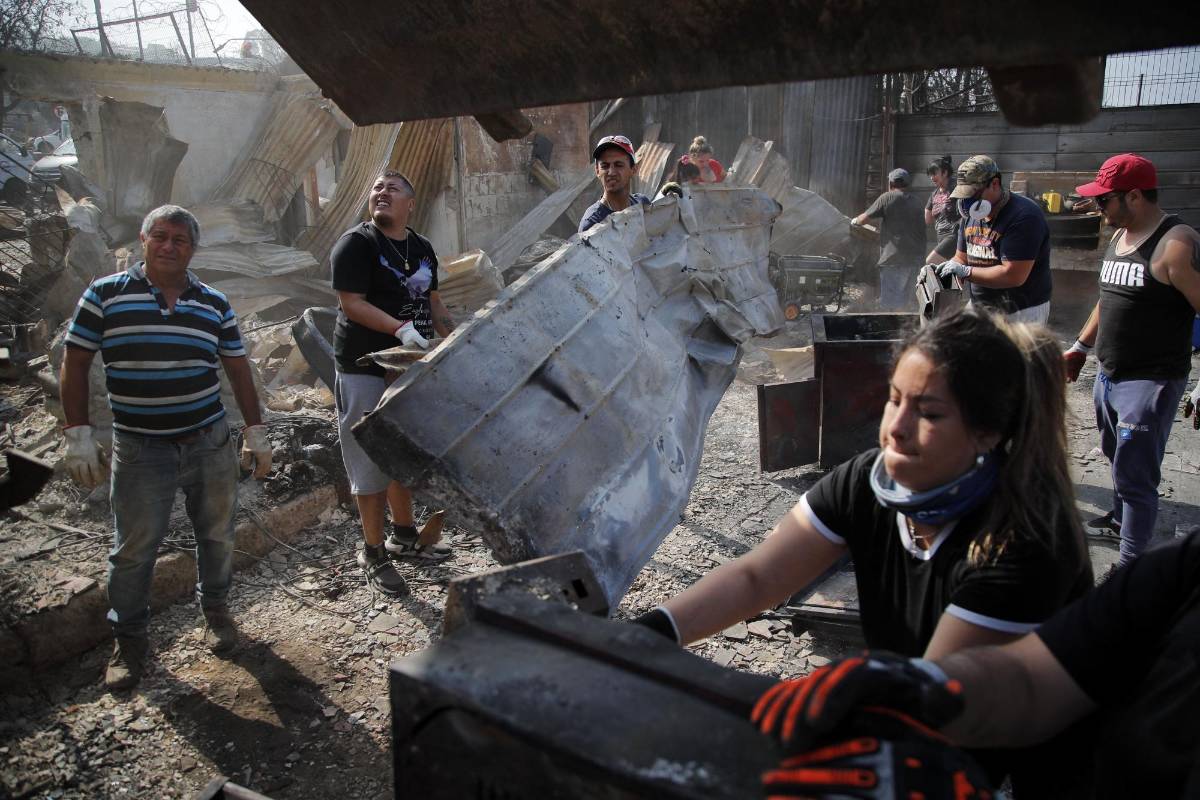 Residentes remueven los escombros de una de las comunidades afectadas por los incendios forestales.