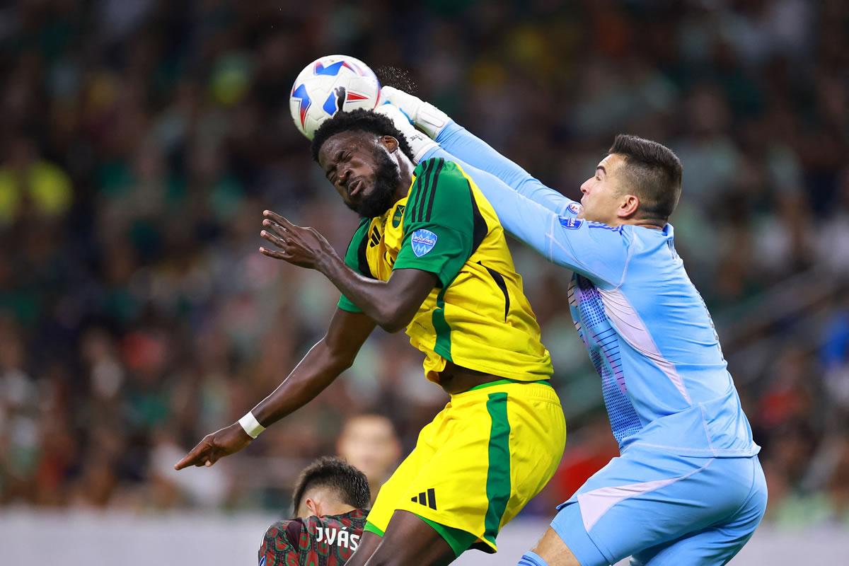 Shamar Nicholson salta por el balón con el portero mexicano Julio González.