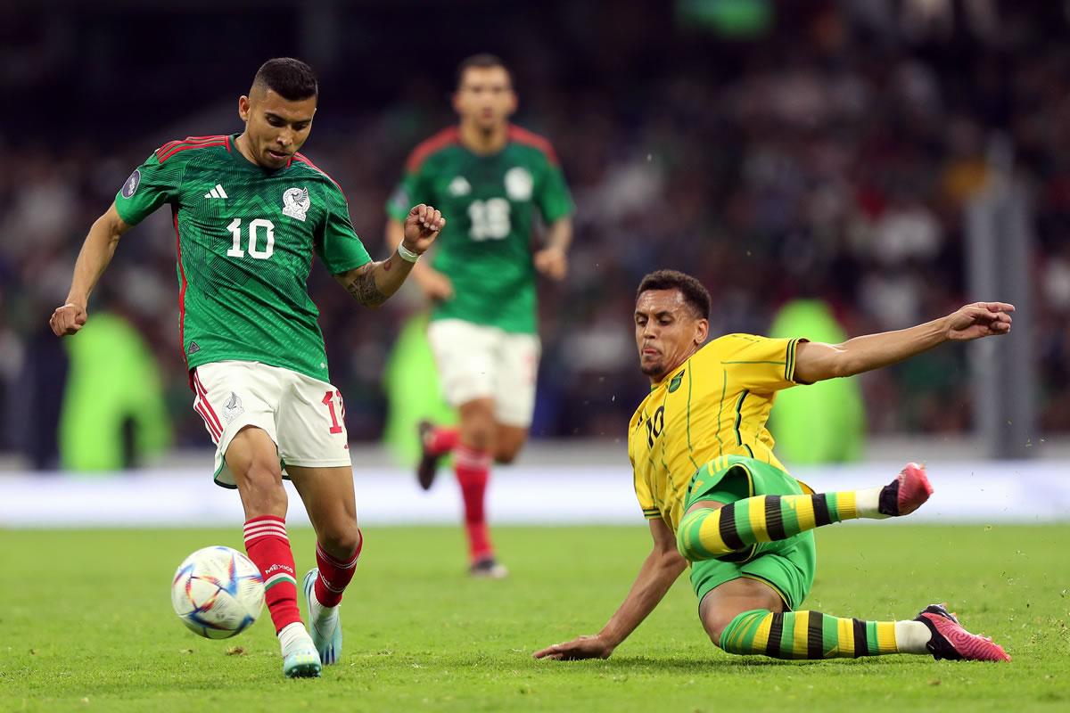 Orbelín Pineda (i) de México controla la pelota ante la marca de Ravel Morrison (d) de Jamaica.