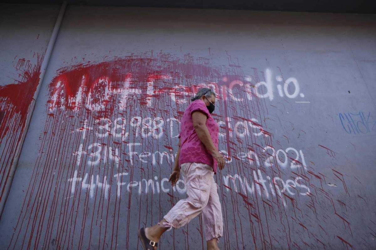 Una mujer camina frente a un aviso pintado en una pared en contra del femicidio hoy en Tegucigalpa