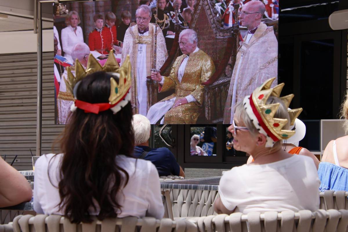 Un grupo de turistas británicos este sábado en Magaluf (Calviá, Baleares), sigue en directo la coronación del rey Carlos III, con coronas de juguete en la cabeza.