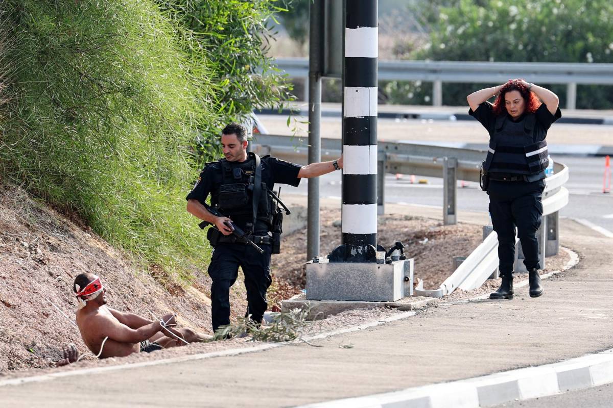 Un prisionero palestino con los ojos vendados habla con un miembro de las fuerzas de seguridad israelíes en la frontera con Gaza, cerca de la ciudad de Ashkelon, en el sur de Israel, el 8 de octubre de 2023.