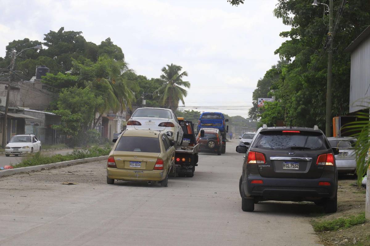 Grúa llevándose dos vehículos turismos en la 27 calle de San Pedro Sula.