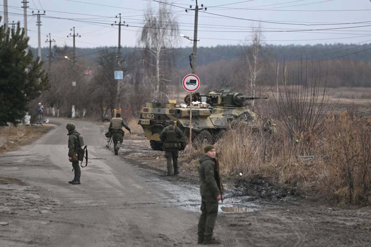 Los militares ucranianos se paran cerca de un vehículo blindado de transporte de personal BTR-3 en el noroeste de Kiev el 24 de febrero de 2022.