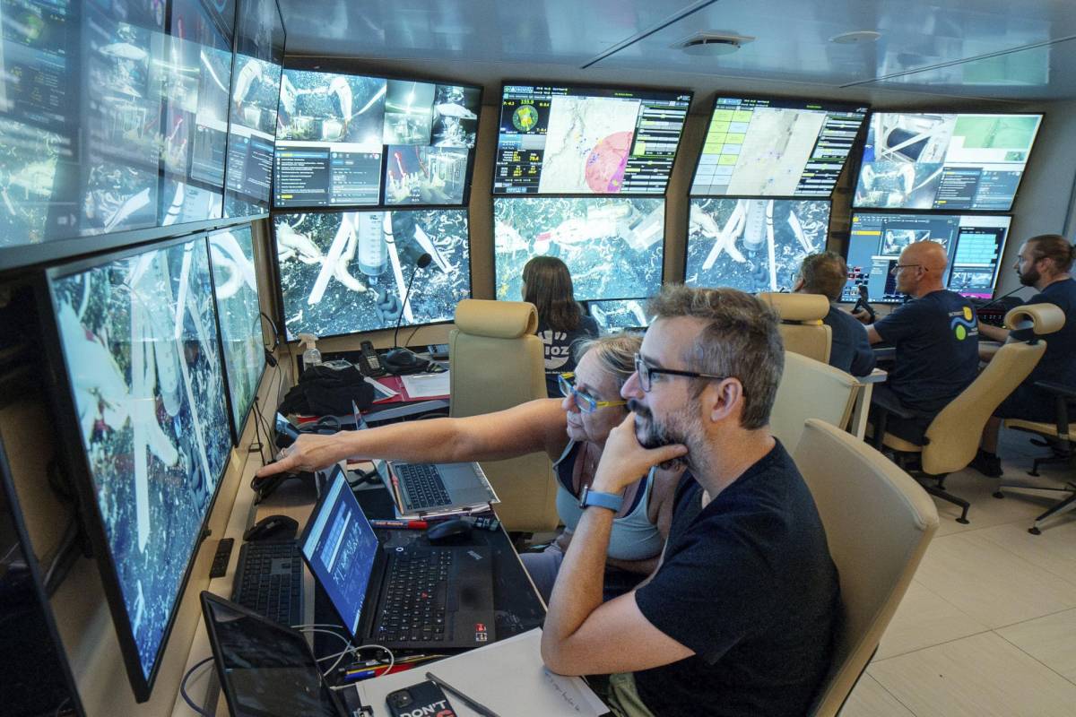 Fotografía muestra a Monika Bright y Andre Luiz de Oliveira trabajando con un vehículo operado por control remoto para volcar trozos de corteza en busca de muestras, a bordo del buque de investigación Falkor (también).