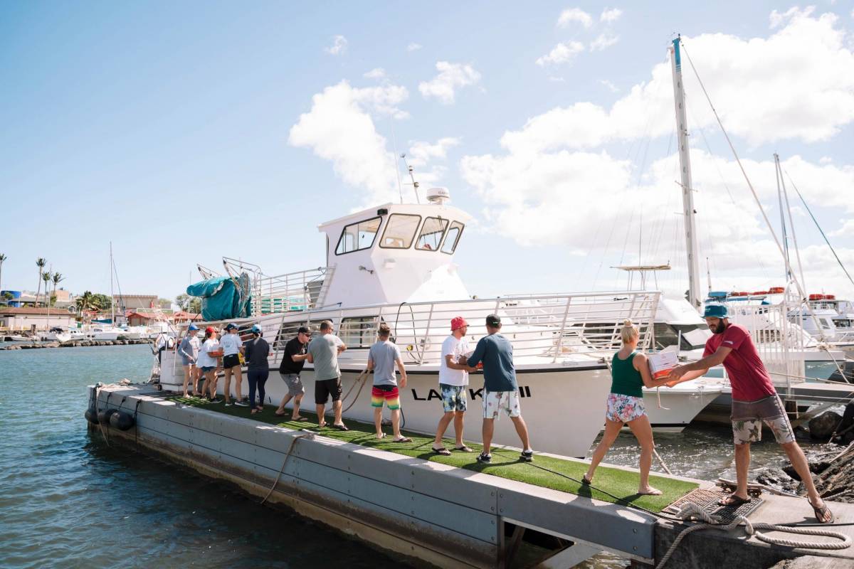 En un esfuerzo por evitar el cierre de carreteras, los voluntarios de la empresa Maui Snorkeling entregan suministros de ayuda para los residentes de Lahaina en barco.