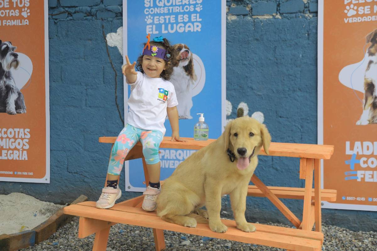 Una niña posa con su mascota en el parque para perros.