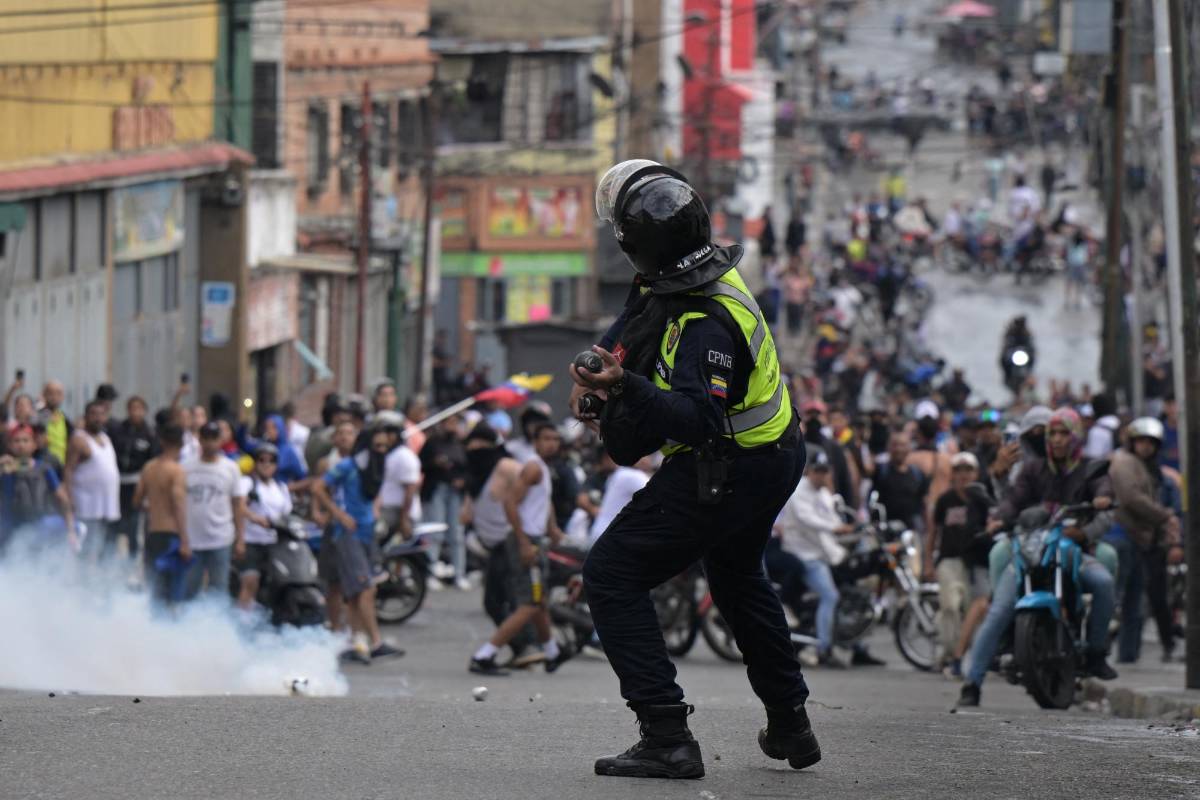 Un oficial de la policía antidisturbios utiliza gases lacrimógenos contra manifestantes durante una protesta de opositores al gobierno del presidente venezolano Nicolás Maduro en el barrio Catia de Caracas el 29 de julio de 2024.