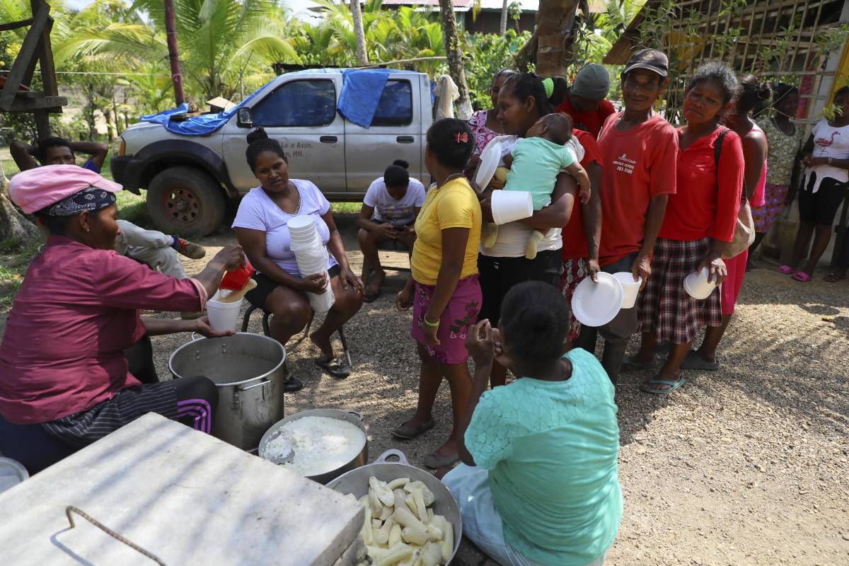 Mujeres hacen fila para recibir una ración de comida durante una olla comunitaria hecha con productos que ellas cosecharon, el 25 de mayo de 2023 en Mocorón, departamento de Gracias a Dios (Honduras).
