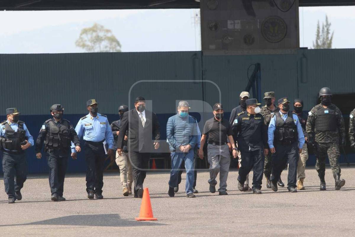 Momento en el que el exmandatario Juan Orlando Hernández, rodeado de autoridades hondureñas, se apresta a abordar una avión de la DEA, que ya vuela rumbo a Nueva York. Fotografía: Opsa