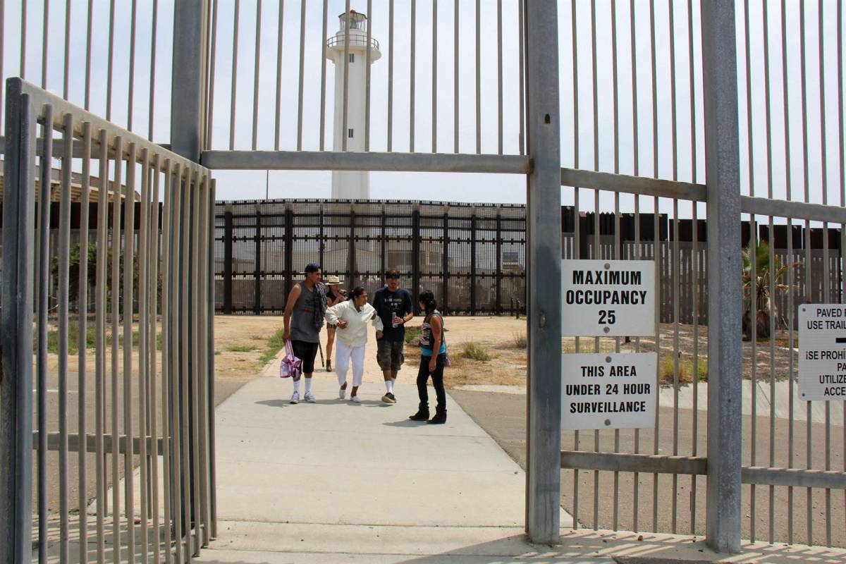 Varias personas salen de la puerta peatonal en el muro secundario del Parque de la Amistad (terminado en 2011) en la frontera de San Ysidro en San Diego, California.